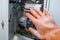 A hand in a dielectric glove opens the door to the electrical panel