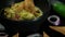 Hand dipping tortilla chip in bowl of guacamole surrounded by tortilla chips