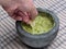 hand dipping tortilla chip into guacamole inside molcajete (mexican mortar and pestle, grinding spices) avocado dip