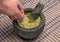 hand dipping tortilla chip into guacamole inside molcajete (mexican mortar and pestle, grinding spices) avocado dip