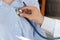 Hand doctor using stethoscope to exam woman patient heart. Doctor listening to young woman patients chest with