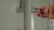 Hand on a door handle of a glass shower cabin in order to open or close it. Shower bulkhead Handle close-up