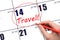 Hand drawing a red circle and writing the text TRAVEL on the calendar date 14 June. Travel planning.