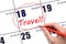 Hand drawing a red circle and writing the text TRAVEL on the calendar date 18 March. Travel planning.