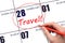 Hand drawing a red circle and writing the text TRAVEL on the calendar date 28 February. Travel planning.