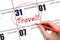 Hand drawing a red circle and writing the text TRAVEL on the calendar date 31 December. Travel planning.