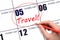 Hand drawing a red circle and writing the text TRAVEL on the calendar date 5 February. Travel planning.