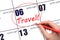 Hand drawing a red circle and writing the text TRAVEL on the calendar date 6 January. Travel planning.