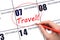 Hand drawing a red circle and writing the text TRAVEL on the calendar date 7 December. Travel planning.