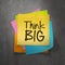 Hand drawn Think BIG phrase on sticky note texture background