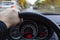 Hand of driver on car wheel and view of dashboard on rainy day in city