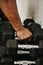 Hand, dumbbell and fitness with a man bodybuilder in a gym for exercise, training or a workout with weights.