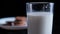 Hand dunking a cookie in glass of milk with black background