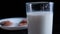 Hand dunking a cookie in glass of milk with black background