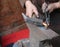 Hand elder blacksmith who uses pliers to shape a hot iron
