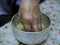 A hand of elderly person dipping into a cup  salung  filled with holy turmeric water
