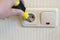 Hand Of An Electrician To Repair A Wall Socket. Closeup of man electrician\'s hand repairing an electrical outlet. Hazardous