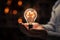 Hand encloses bulb, gears within, depicting business acumen and ingenuity