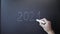 Hand erases from board 2021 and writing 2022 on blackboard with chalk. Male hand writing 2021-2022 year on chalkboard. Man writes