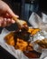 Hand of a female dipping hot wings in a condiment sauce