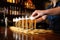 hand filling a line of pint glasses with wheat beer at a bar