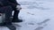 Hand of fisherman catches fish on winter fishing rod on frozen river with hole