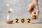 hand flipping block 2023 to 2024 text with hourglass on table. Resolution, time, plan, goal, motivation, reboot, countdown and