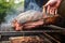 hand flipping brisket on a smoking grill rack