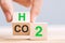 Hand flipping wooden cube blocks with CO2 Carbon dioxide, change to H2 Hydrogen text on table background. Free Carbon,