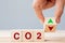 Hand flipping wooden cube blocks to UP and Down arrow symbol with CO2 Carbon dioxide text on table background. Free Carbon,