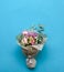 Hand flower bouquet consists of chrysanthemum, roses and green leaves on blue background