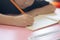 Hand focusing of adorable asian child girl is writing and reading on her paper book in the room at home with sunlight shows