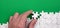 The hand folds a white jigsaw puzzle against the background of the green surface. Texture photo with space for text