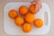 Hand on the fresh citrus oranges on the white cutting board