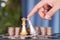 A hand in front of a large number of dollar coins helps the silver queen chess piece to defeat the golden queen chess piece