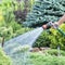 Hand garden hose with water spray, watering flowers, close-up, water splashes, landscape design, alpine slide