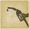 Hand with gasoline fuel nozzle on vintage background