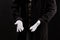 Hand gestures. Showman or magician illusionist in white gloves on a black background.