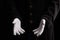 Hand gestures. Showman or magician illusionist in white gloves on a black background.