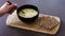 Hand getting spoonful of vegetable soup with textured vegetable protein next to wholegrain crackers