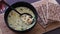 Hand getting spoonful of vegetable soup with textured vegetable protein next to wholegrain crackers