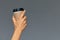 Hand of a girl holding a paper cup of coffee, gray background Good morning, concept. Empty place for an inscription.