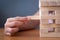 Hand of a girl placing and pulling wooden block on the tower