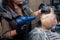 The hand of a girl of a professional hairdresser stylist blow-dry the hair of an adult client in a barbershop