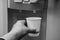 A hand with a glass pours cold water from a cooler. Close-up.