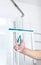 Hand with glass scraper cleans glass in shower