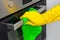 Hand in glove with green rag is wiping oven in kitchen