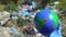 Hand in glove holding Earth globe with cross sign against landfill background