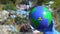 Hand in glove showing Earth globe with radiation sign, landfill on background