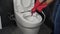 Hand in gloves cleaning toilet bowl with brush